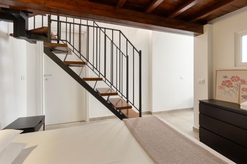 Interno moderno dell'appartamento LM Apartments Pavia con scala in legno, travi a vista e arredamento minimalista