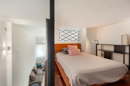 Camera moderna presso LM Apartments Pavia con letto in legno, cuscini rosa e vista sulla città