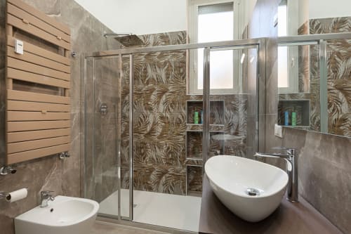 Bagno moderno presso LM Apartments Pavia con doccia in vetro, vasca indipendente e piastrelle con motivi vegetali