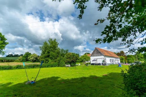 Cottage blanc avec terrasse entouré d'un jardin verdoyant aux Gîtes du Clubhouse à Beussent, France