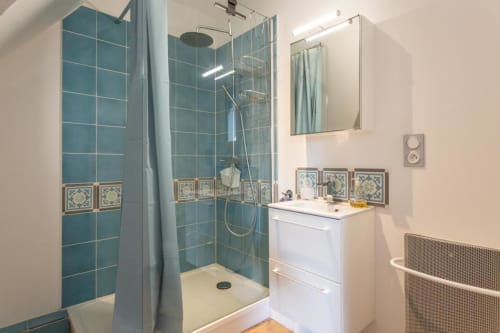 Modern bathroom at Clubhouse Gîtes with teal tile shower, white sink, and illuminated mirror