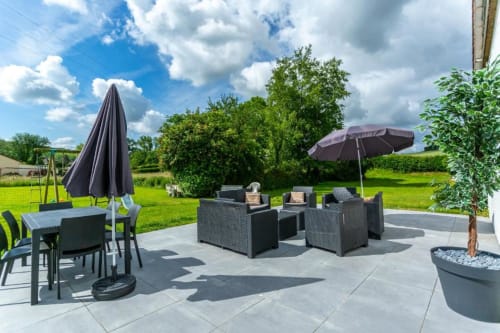 Terrasse extérieure du Clubhouse Gîtes à Beussent avec mobilier de jardin, parasols et vue sur le jardin