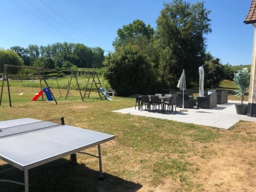 Espace jardin aux Gîtes du Clubhouse à Beussent avec table de ping-pong, aire de jeux, terrasse de dining et aménagement paysager verdoyant.