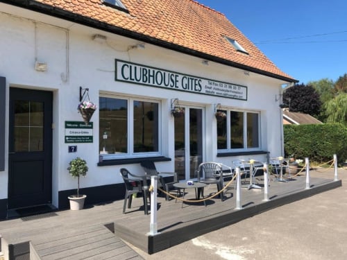 Entrée des Gîtes Clubhouse à Beussent avec terrasse, bâtiment blanc, toit de tuiles oranges et vue sur le jardin