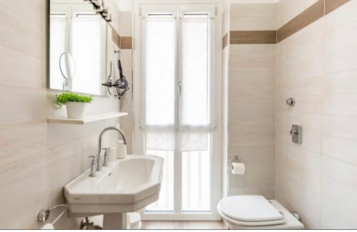 Bagno moderno negli appartamenti LM Apartments Pavia con lavabo, water, doccia, specchio e finestre