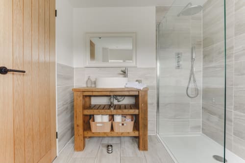 Modern bathroom in Stevenage villa with wooden vanity, white vessel sink, walk-in shower, and heated towel rails
