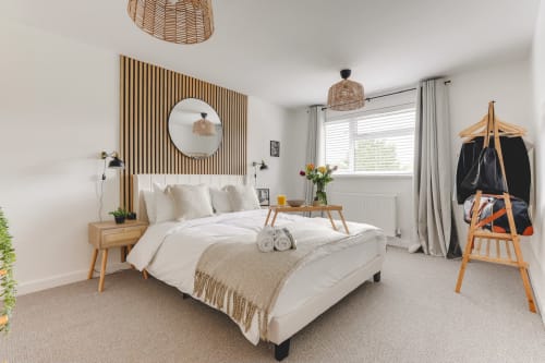 Luxurious 2-bedroom villa in Stevenage with garden view, featuring modern bed, wooden accent wall, and contemporary