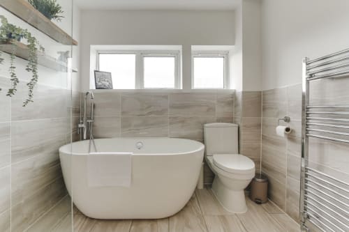 Modern luxury bathroom in Stevenage villa with freestanding white bathtub, contemporary fixtures, heated towel rail, and