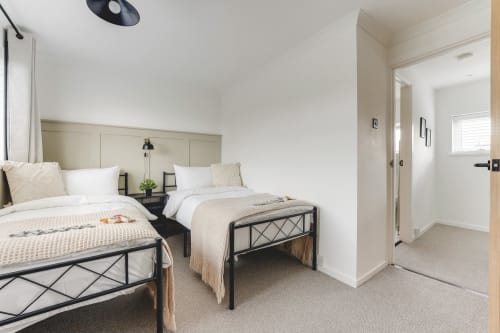 Modern twin bedroom at Towerserve Properties Stevenage villa with garden view, featuring two beds, neutral decor, and