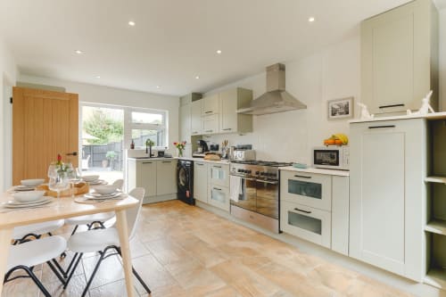 Modern cream kitchen with dining area, stainless steel appliances, and garden views in Stevenage luxury villa