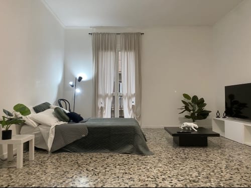 Camera da letto Modern LM Apartments Pavia con letto, pavimento in terrazzo, vista città dalle porte-finestre e arredamento contemporaneo
