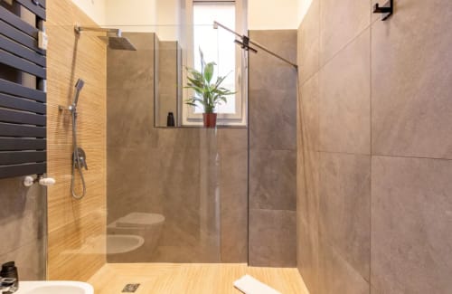Moderno bagno presso LM Apartments Pavia con doccia walk-in, piastrelle beige e vista dalla finestra