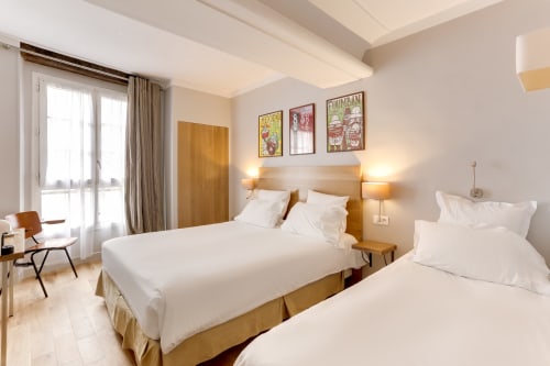 Chambre Triple Confort à l'Hôtel Louvre Richelieu à Paris avec deux lits, mobilier en bois et équipements modernes