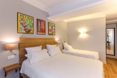 Chambre Triple Confort à l'Hôtel Louvre Richelieu à Paris avec deux lits, tête de lit en bois et décoration murale aux motifs mexicains