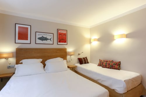 Chambre Double Supérieure de l'Hôtel Louvre Richelieu à Paris avec deux lits, tête de lit en bois et équipements modernes
