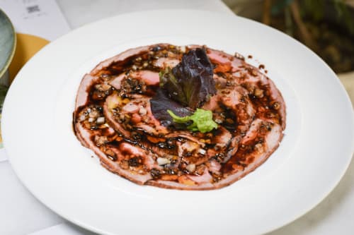 Plato gourmet del hotel Huerta Honda en Zafra: carne sellada, salsa caramelizada y guarnición de hierbas aromáticas