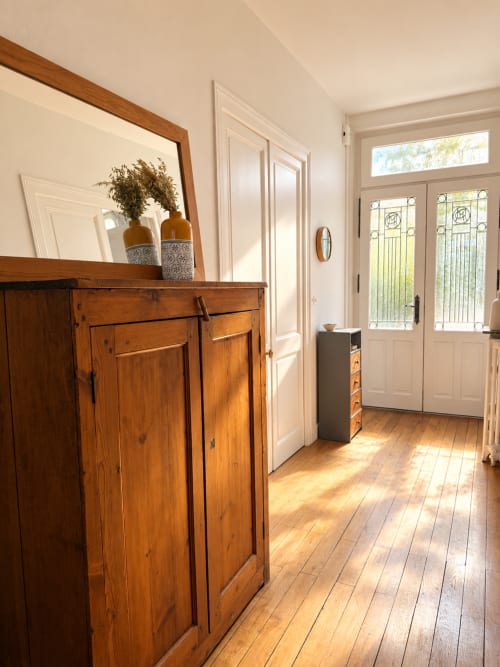 Entrée lumineuse avec mobilier en bois, miroir et portes vitrées doubles à la Villa Cognehors à La Rochelle