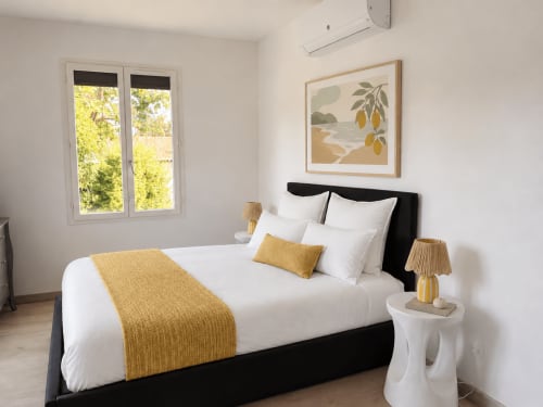 Chambre Villa Alba d'ARLOÉ La Rochelle avec lit noir, draps blancs, détails dorés et vue sur le jardin