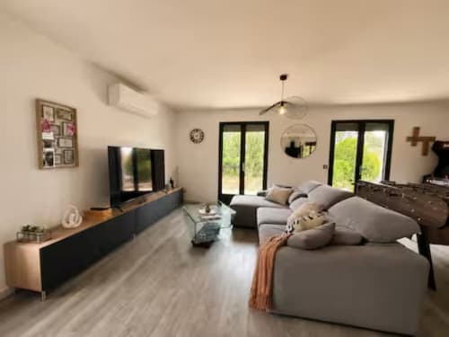 Villa Alba à ARLOÉ La Rochelle - spacieux séjour avec canapé gris moderne, TV et vue sur le jardin