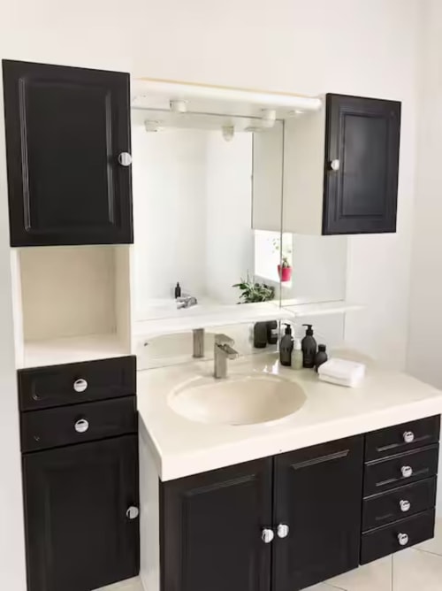 Salle de bains moderne à la Villa Alba ARLOÉ, La Rochelle, avec meubles noirs, plan de travail blanc et miroir