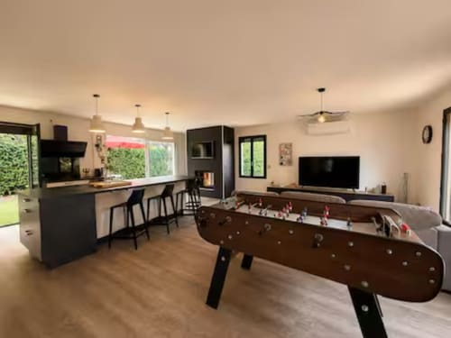 Salle de loisirs Villa Alba avec baby-foot, îlot de cuisine, TV et vue sur le jardin à ARLOÉ, La Rochelle