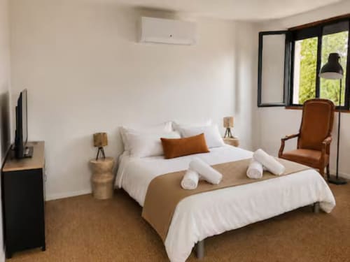 Chambre moderne de la villa ARLOÉ La Rochelle avec literie blanche, accents marron, mobilier en bois et climatisation