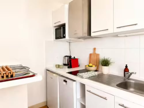 Cuisine blanche contemporaine de l'appartement ARLOÉ à La Rochelle, équipée d'un évier inox, cuisinière et équipements de base