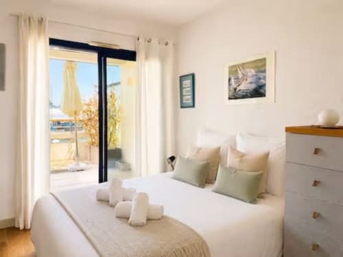 Chambre lumineuse avec lit blanc, balcon vue sur la rivière et équipements modernes à l'appartement ARLOÉ à La Rochelle