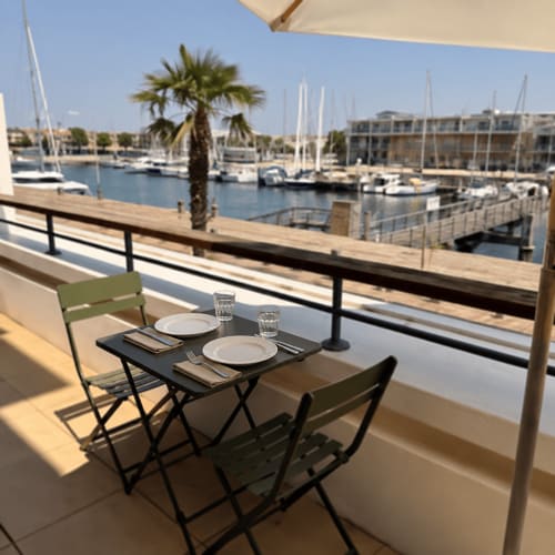 Table dressée pour deux sur un balcon avec vue sur le port de La Rochelle, voiliers et palmier