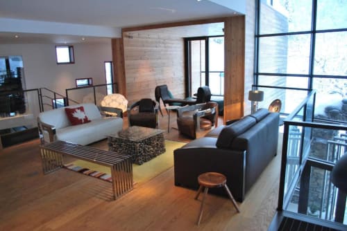 Salon moderne du Chalet Violettes à Villaroger avec sièges en cuir noir, canapé blanc et poutres bois