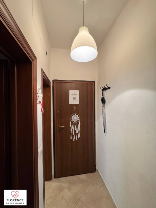 Corridoio moderno in appartamento fiorentino con lampada a sospensione, porte in legno e acchiappasogni decorativo