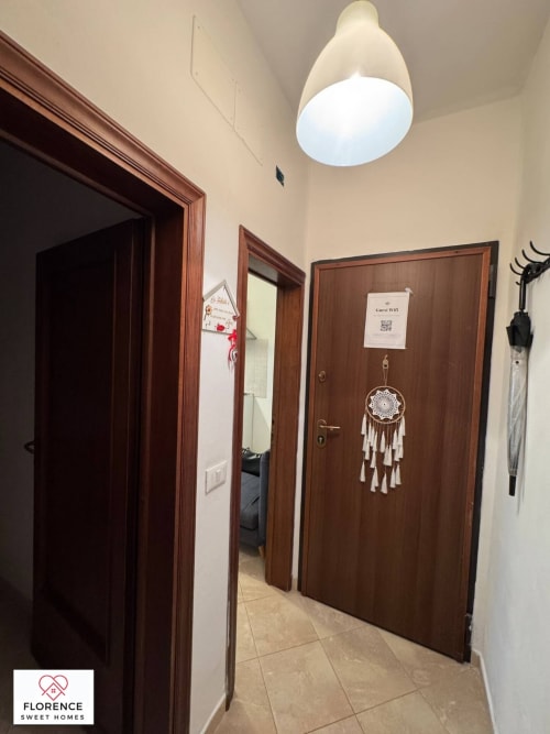 Corridoio dell'appartamento Florence Sweet Homes con porte in legno, lampada a soffitto bianca, decorazione acchiappasogni e WiFi ospiti