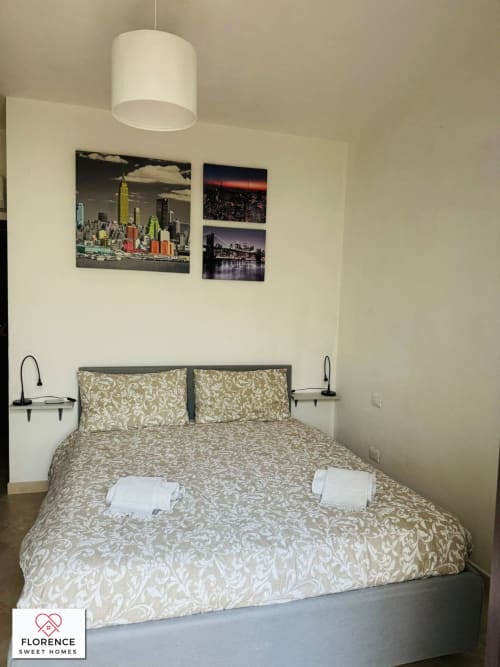Camera accogliente di appartamento fiorentino con biancheria decorata, arte urbana, lampada a sospensione e comfort moderni