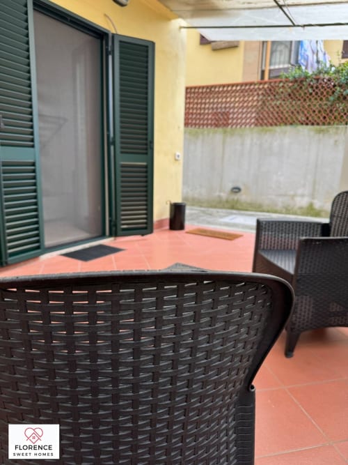 Terrazza esterna di Florence Sweet Homes con sedie in vimini, patio in terracotta e muri gialli