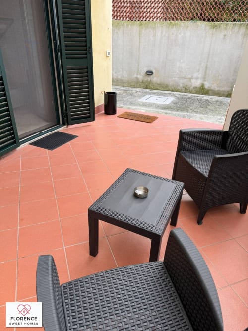 Patio in terracotta con mobili in vimini presso Florence Sweet Homes, con zona pranzo all'aperto e persiane verdi