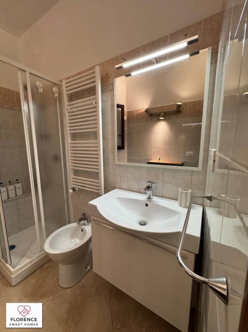 Bagno moderno nell'appartamento Florence Sweet Homes con lavandino bianco, WC, scaldasalviette e specchio illuminato