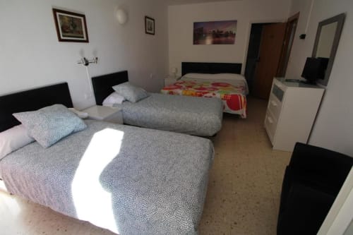 Amplia habitación cuádruple en Hostal Fornet Altea con múltiples camas, equipamientos modernos y vistas a la ciudad