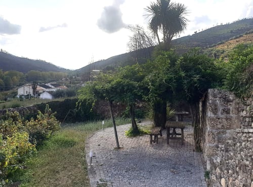 Pátio ajardinado da Villa Alzira em Seia com terraço pavimentado, mobiliário em madeira, palmeira e vistas para a serra