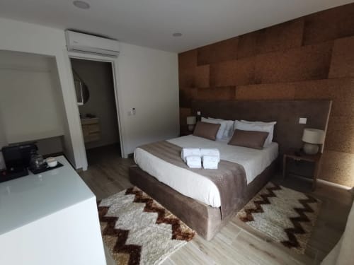 Quarto moderno da Villa Alzira com cama queen, parede de cortiça marrom, roupa de cama branca e mobiliário contemporâneo em Seia