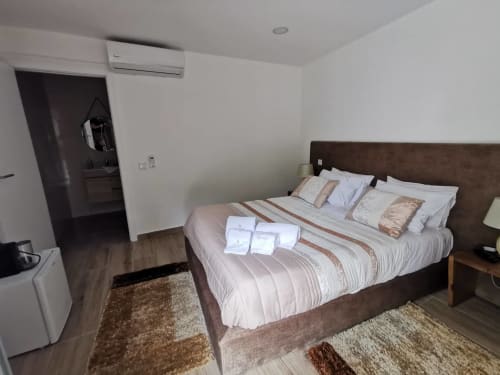 Quarto moderno da Villa Alzira em Seia com cama de casal, cabeceira escura, roupa branca, assoalho de madeira, ar condicionado e