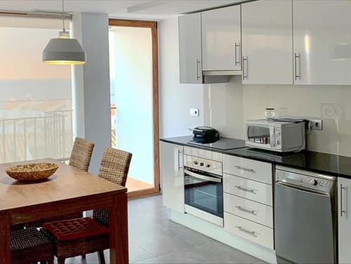 Cocina y comedor modernos en apartamento de Hostal Fornet Altea con acceso a balcón con vistas al mar