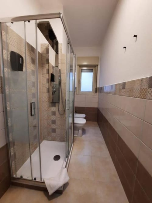 Bagno moderno in Messina B&B con doccia in vetro, toilet e dettagli in piastrelle marroni