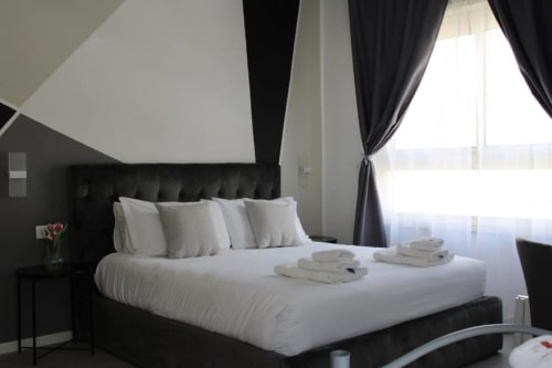 Camera moderna presso U Baruni b&b a Messina con letto rivestito nero, biancheria bianca, asciugamani freschi, vista città e