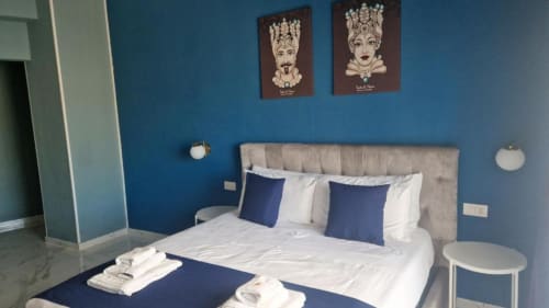 Camera moderna dell'U Baruni b&b di Messina con pareti blu, letto beige, cuscini blu navy e decorazioni artistiche