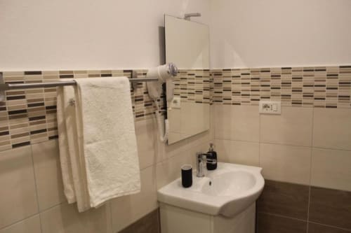 Bagno moderno nella Family Room di U Baruni b&b, Messina con lavabo bianco, rivestimenti in piastrelle, portasciugamani e specchio