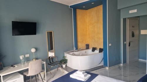 Bagno suite moderno presso U Baruni b&b a Messina con vasca idromassaggio angolare, pareti blu, piastrelle gialle e scrivania