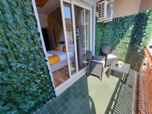 Balcone dell'U Baruni b&b a Messina con muri ricoperti di edera, zona relax e vista della camera da letto attraverso porte in vetro
