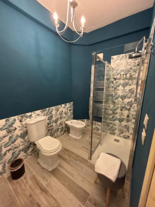 Bagno moderno con pareti turchesi, dettagli decorativi botanici, doccia a filo pavimento e finiture eleganti a Villa Brikinnia a Lentini