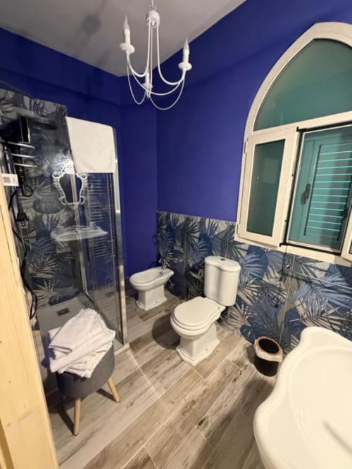 Bagno moderno di Villa Brikinnia con pareti blu vivaci, doccia walk-in, doppi wc, dettagli in piastrelle tropicali e arco