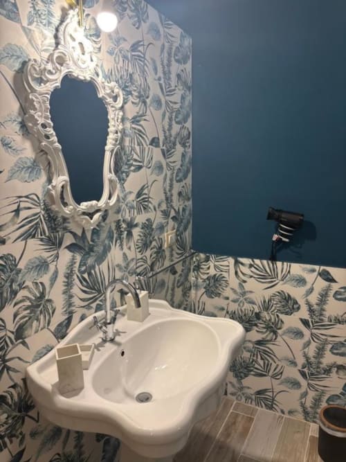 Bagno moderno di Villa Brikinnia con carta da parati a motivi botanici, lavabo bianco su piedistallo, specchio ornamentale e design contemporaneo
